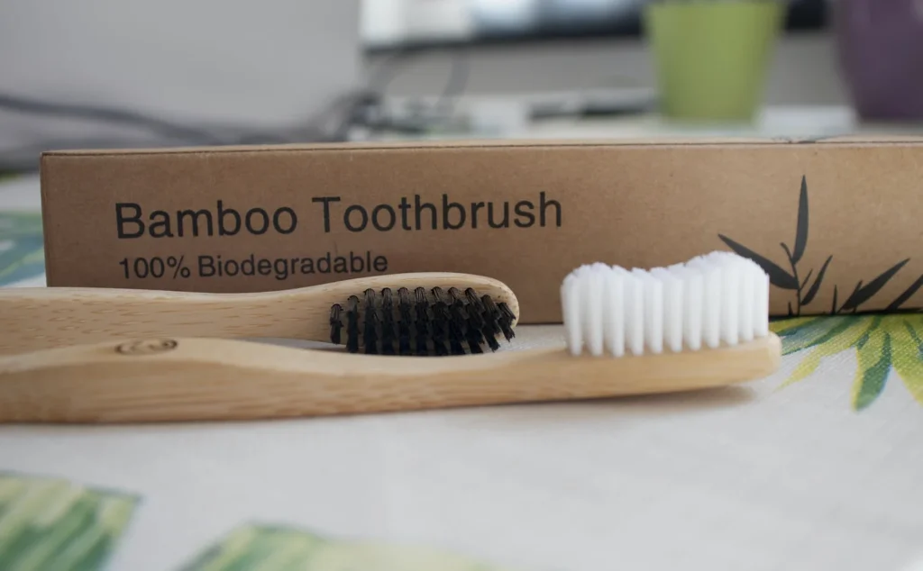 Bamboo toothbrushes with charcoal bristles in a glass jar.