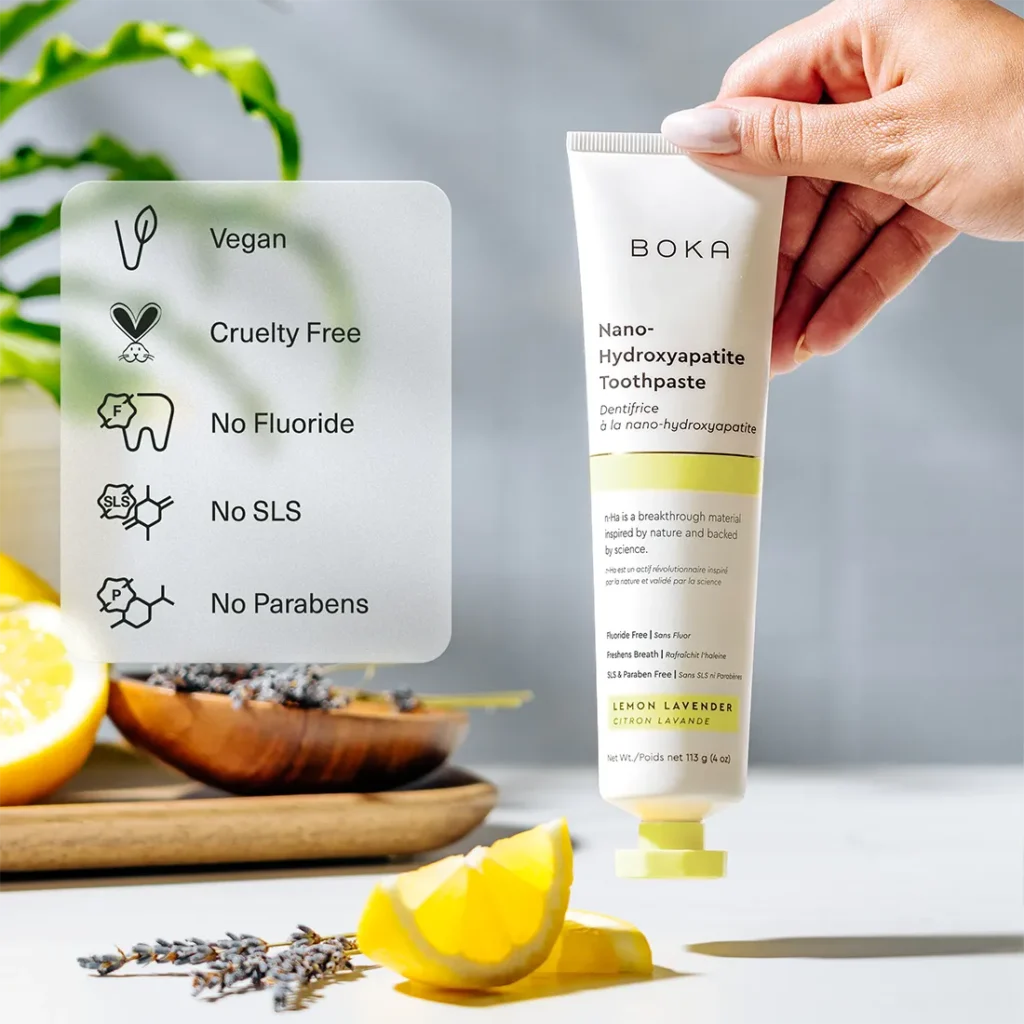 A hand holding a tube of Boka toothpaste lemon lavender flavor next to a feature list detailing its vegan, cruelty-free, fluoride-free, SLS-free, and paraben-free formulation.