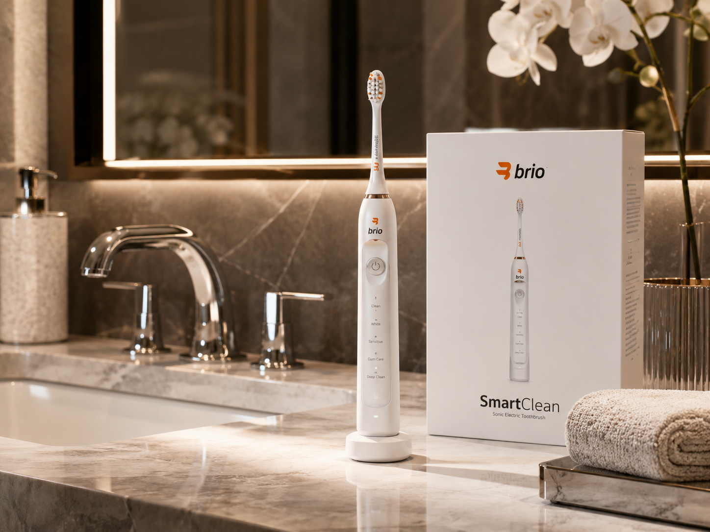 Brio Ollie SmartClean electric toothbrush beside its box on a premium marble sink in a luxury bathroom.