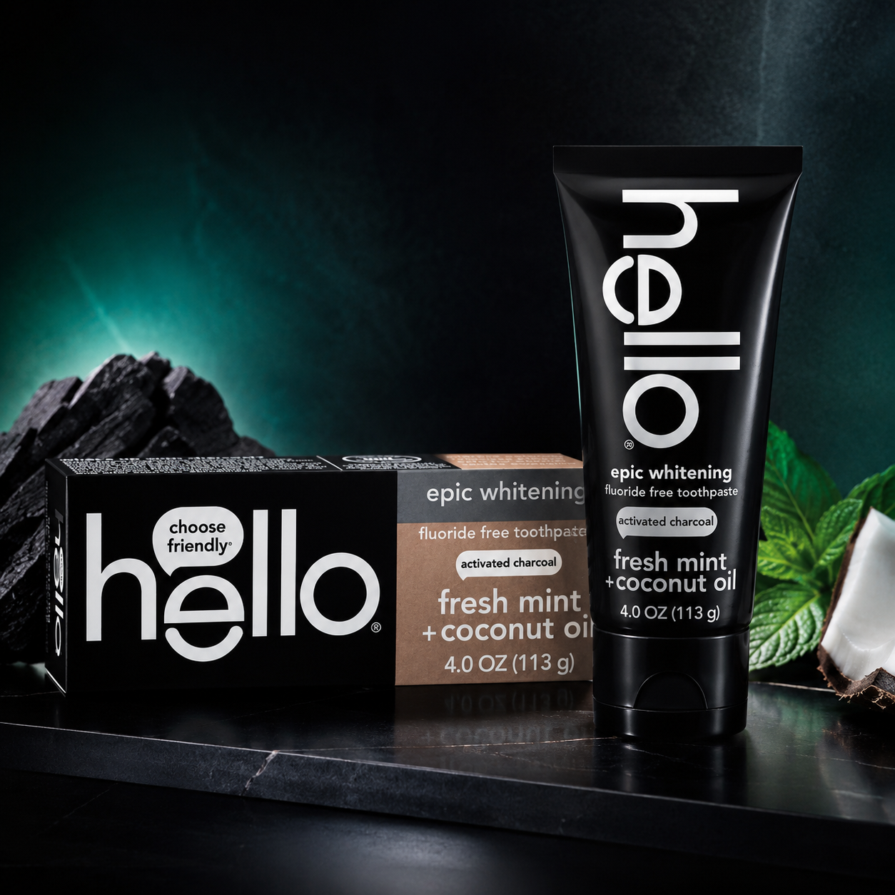 Hello activated charcoal fluoride whitening toothpaste displayed with charcoal, fresh mint leaves, and coconut in a dramatic premium setting.